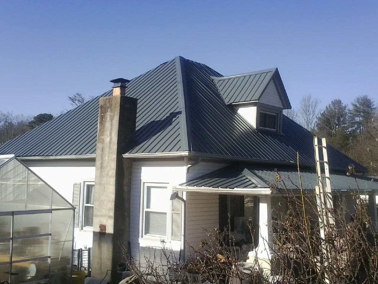 Dark blue standing seam metal roof on a white farmhouse with dormer — Slate & Tile Roof Repair by Roofing Brothers in Magalia