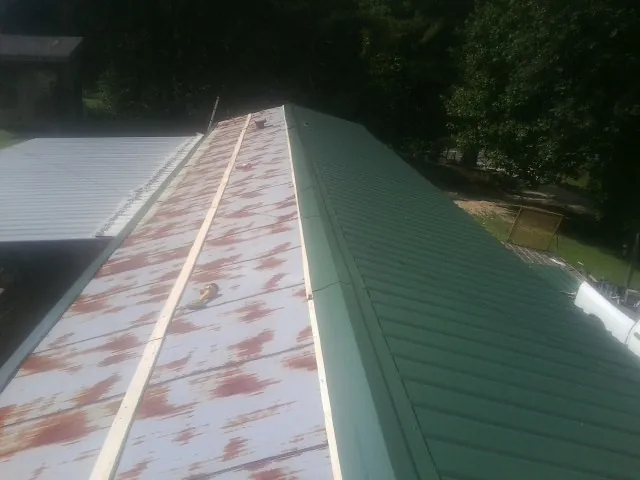 Old rusted panels beside newly installed green metal roofing — Wind Damage Roof Repair by Roofing Brothers in Magalia