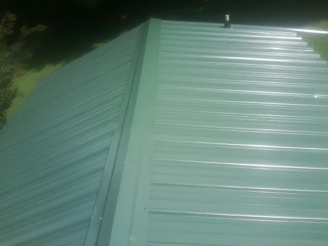 New green metal panels meeting at the ridge of a roof — Flat Roof Repair work by our crew in Magalia