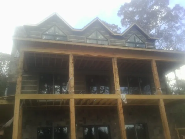 Dormers and porch framing on a large log home under construction — Roof Coating work by our crew in Magalia
