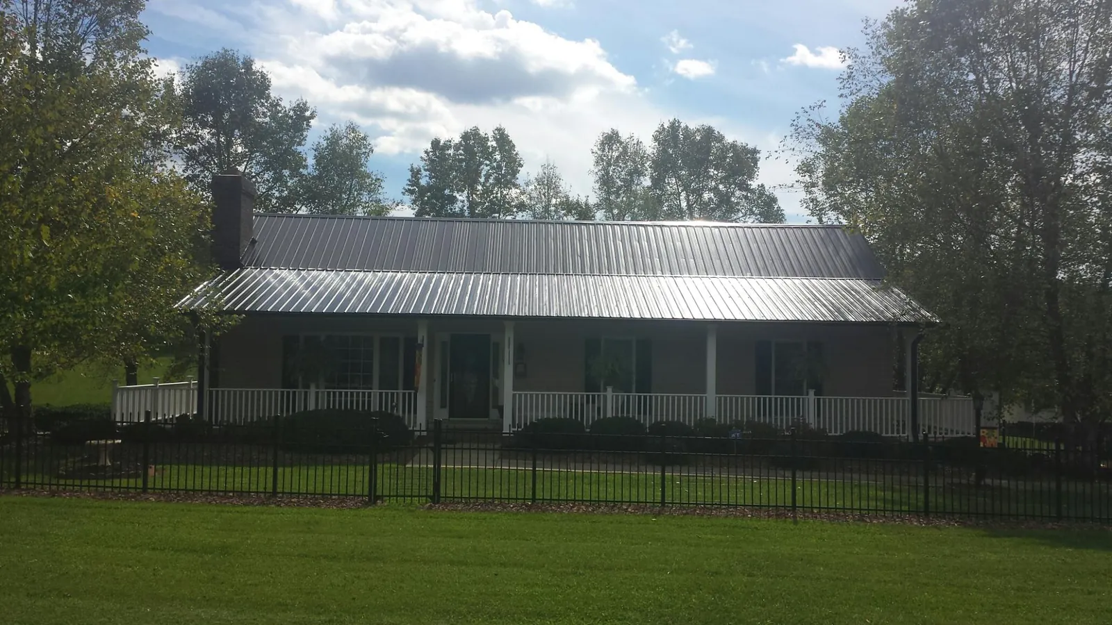Gray metal roof on a brick ranch with a full width front porch — Gutter Guard Installation work by our crew in Magalia