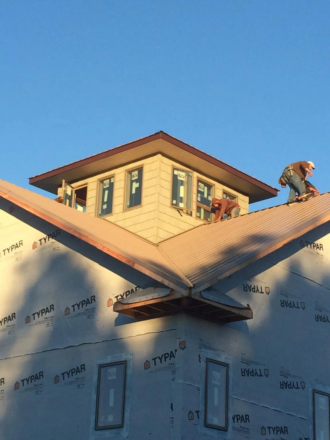 Roofers working around a rooftop cupola on a new metal roof at sunset — Roof Waterproofing in Magalia by Roofing Brothers